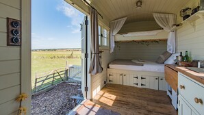 Ein gemütliches Schlafzimmer mit Etagenbett, Holzboden und Blick auf eine grüne Wiese.