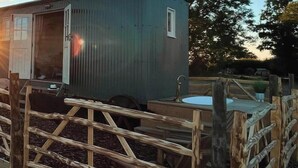 Eine rustikale Holzhütte mit einer Holzterrasse, einem kleinen Außenspülbecken und einem Fenster.