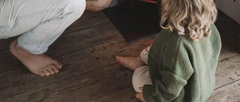 A man and a child sitting on the floor in front of a fireplace.