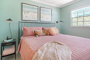 A bedroom with a bed, two wall-mounted lamps, a nightstand, and a window with blinds.