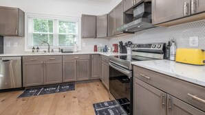 Une cuisine moderne dotée d’appareils électroménagers en acier inoxydable, d’un grille-pain jaune et de meubles en bois.