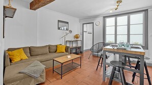 Ein Wohnzimmer mit einer Couch, einem Couchtisch und einem Essbereich mit Tisch und Stühlen.