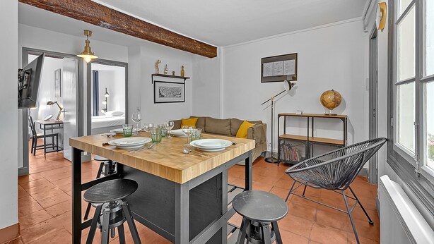 Eine moderne Küche mit einer Holztheke, schwarzen Barhocker und einem schwarzen Stuhl aus Draht.