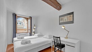 Ein Schlafzimmer mit zwei Betten, einem Schreibtisch und einem Stuhl.