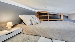 Une chambre à coucher comprenant un lit, une table de chevet, une lampe et une étagère en bois.