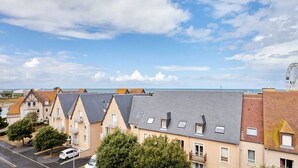 Un quartier résidentiel situé sur la côte, avec des maisons, un ciel dégagé et une vue lointaine sur la mer.