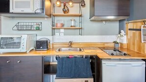 Une cuisine compacte équipée d’un four à micro-ondes, d’un grille-pain, d’un évier et d  ’un lave-vaisselle.