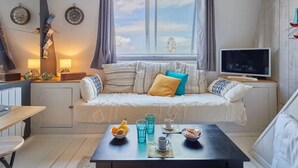 Une pièce confortable avec un canapé, une table avec des boissons et des en-cas, un téléviseur et une fenêtre avec des rideaux.