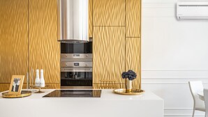 Eine moderne Küche mit einer zentralen Kochinsel, Edelstahlgeräten und einer Wand mit Holzoptik.