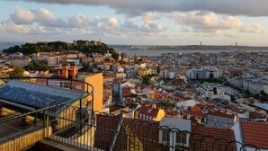 Ein weiter Blick auf eine Stadtlandschaft mit einem markanten Hügel und einer Brücke im Hintergrund.