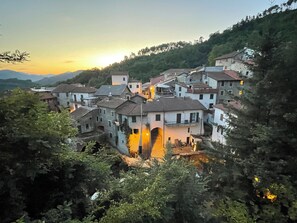 A hillside village with traditional architecture, including stone buildings with sloped roofs and a central building with a prominent archway. - House in the woods 15 km from the 5 Terre (Rio di sesta godano)