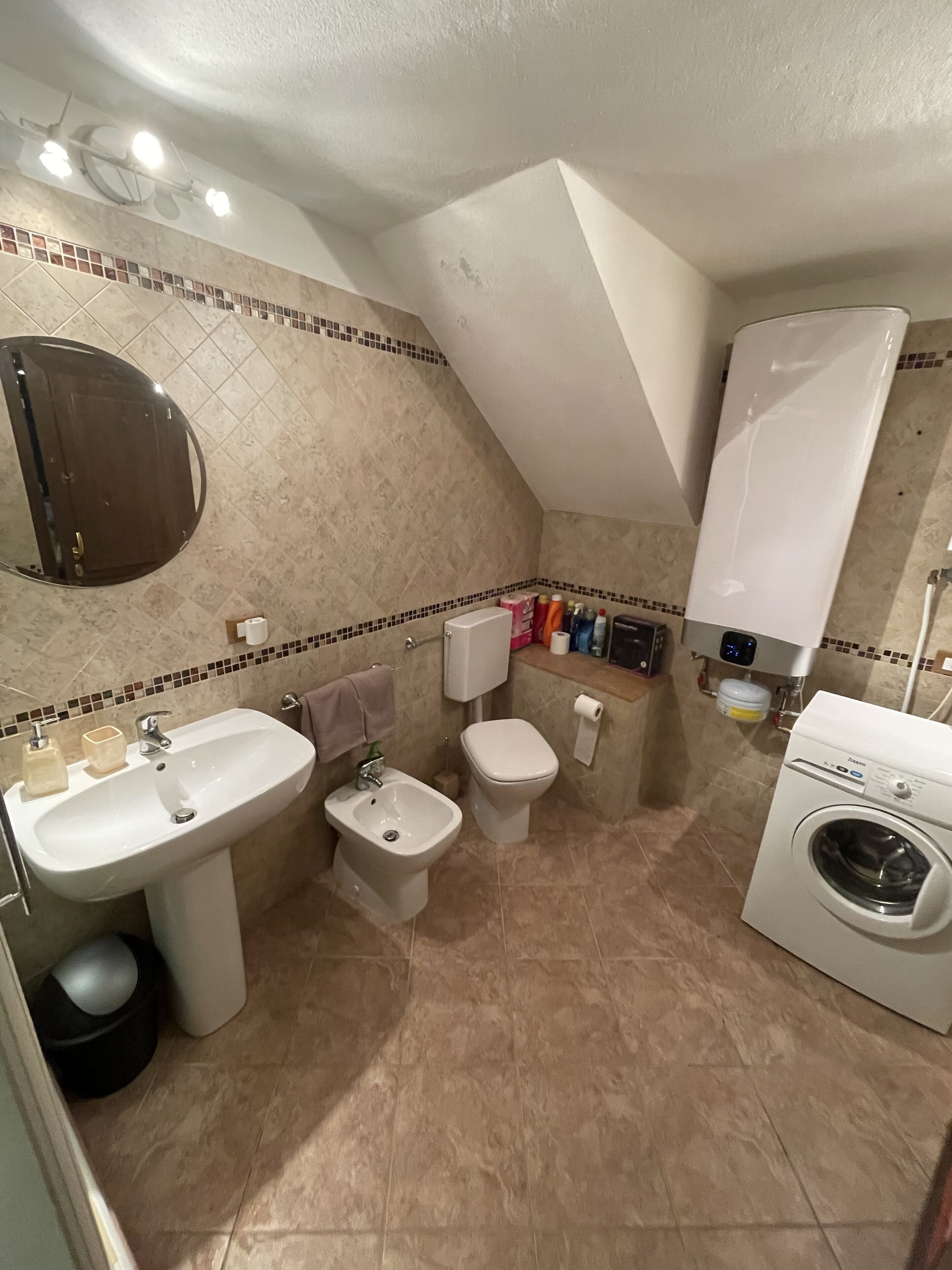A compact bathroom with a sink, bidet, toilet, and washing machine.