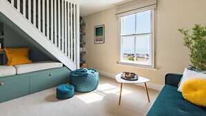 Una sala de estar moderna con una escalera, una ventana con vistas, una mesita y un sofá.