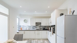 Een moderne keuken met witte kasten, een betegelde spatwand en een roestvrijstalen koelkast.
