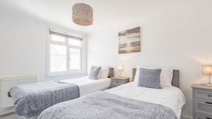 Een slaapkamer met twee bedden, een raam, een lamp en een schilderij aan de muur.