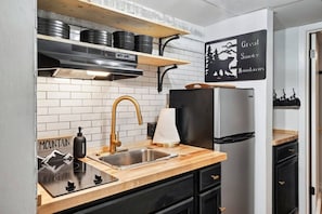 Una cucina con lavello in acciaio inossidabile, frigorifero nero e piano di lavoro in legno.