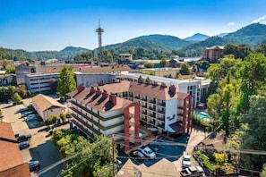 Un hôtel à plusieurs étages doté d’une piscine sur le toit, entouré de verdure et de montagnes.