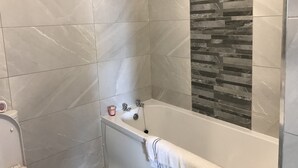 Un baño con bañera, ducha y retrete.