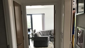 Un pasillo que conduce a una sala de estar con un sofá y una mesa de comedor.