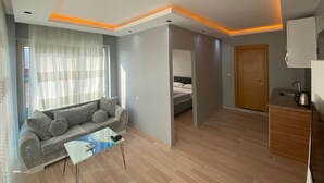 Een moderne woonkamer met een bank, salontafel, en een bed in de aangrenzende kamer.