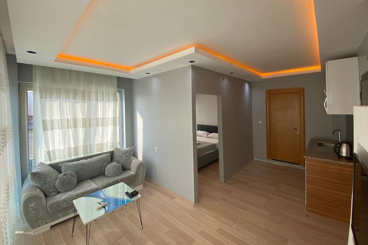 Uma sala de estar moderna com sofá, mesa de centro e uma cama no quarto adjacente.