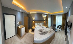 Une chambre d’hôtel moderne équipée d’un grand lit, de tables de chevet, d’un bureau, d’une armoire et d’un téléviseur.