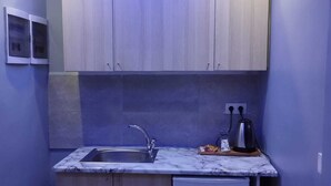 Een kleine keuken met een gootsteen, een koelkastje en houten kastjes.