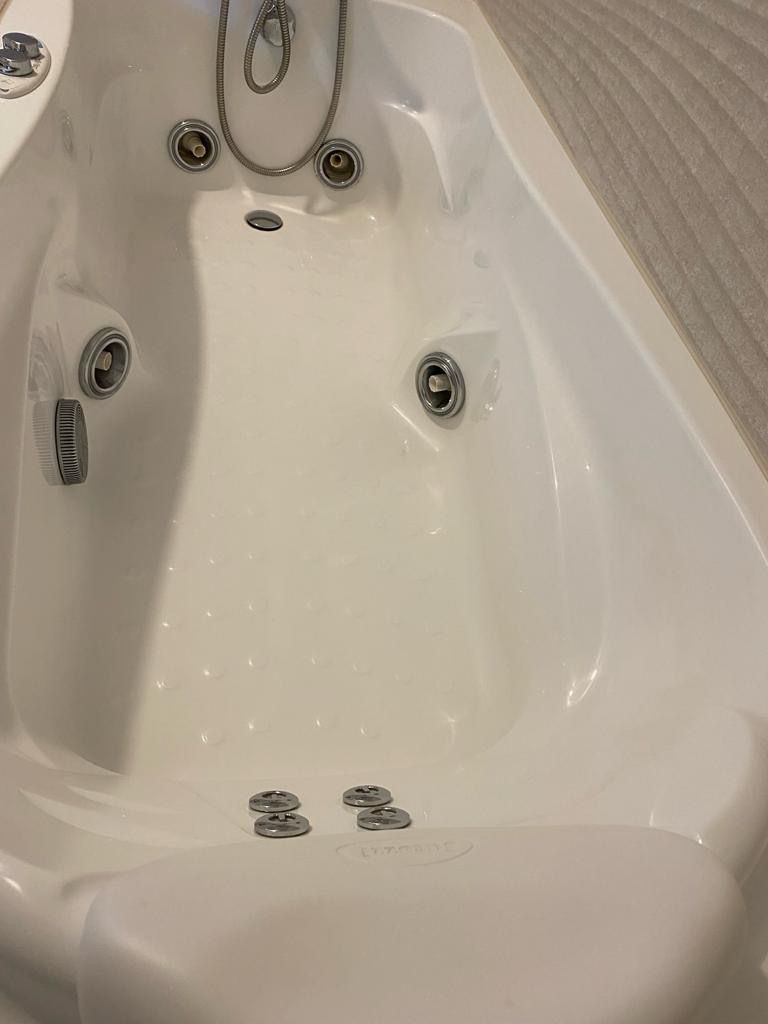 A bathtub with a built-in showerhead and multiple faucets.