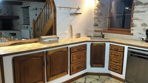 A kitchen with a stone floor, wooden cabinets, a built-in dishwasher, and a window with a view.