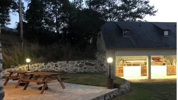 A stone patio with a picnic table, a stone wall, and a house with a garage and a covered area.