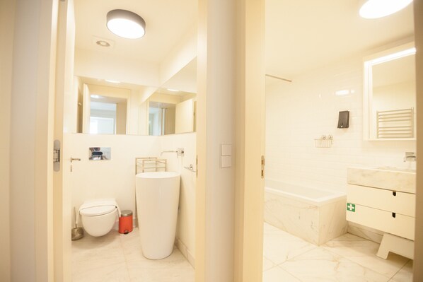 A modern bathroom with a toilet, sink, and bathtub.