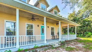 A two-story house with a covered porch, a front door, and a small garden area. - Lovely Hawthorne Home w/ Private Boat Dock! (Hawthorne)