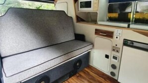 Una cocina compacta con microondas, un lavamanos y una zona de estar con bancos.