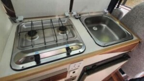 Una kitchenette compacta con estufa a gas y pileta.