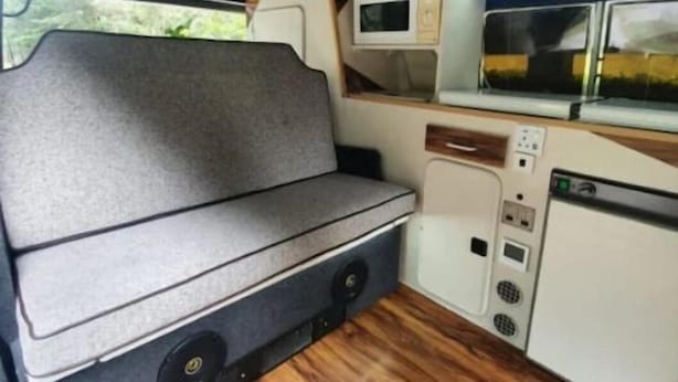 Una cocina compacta con microondas, un lavamanos y una zona de estar con bancos.