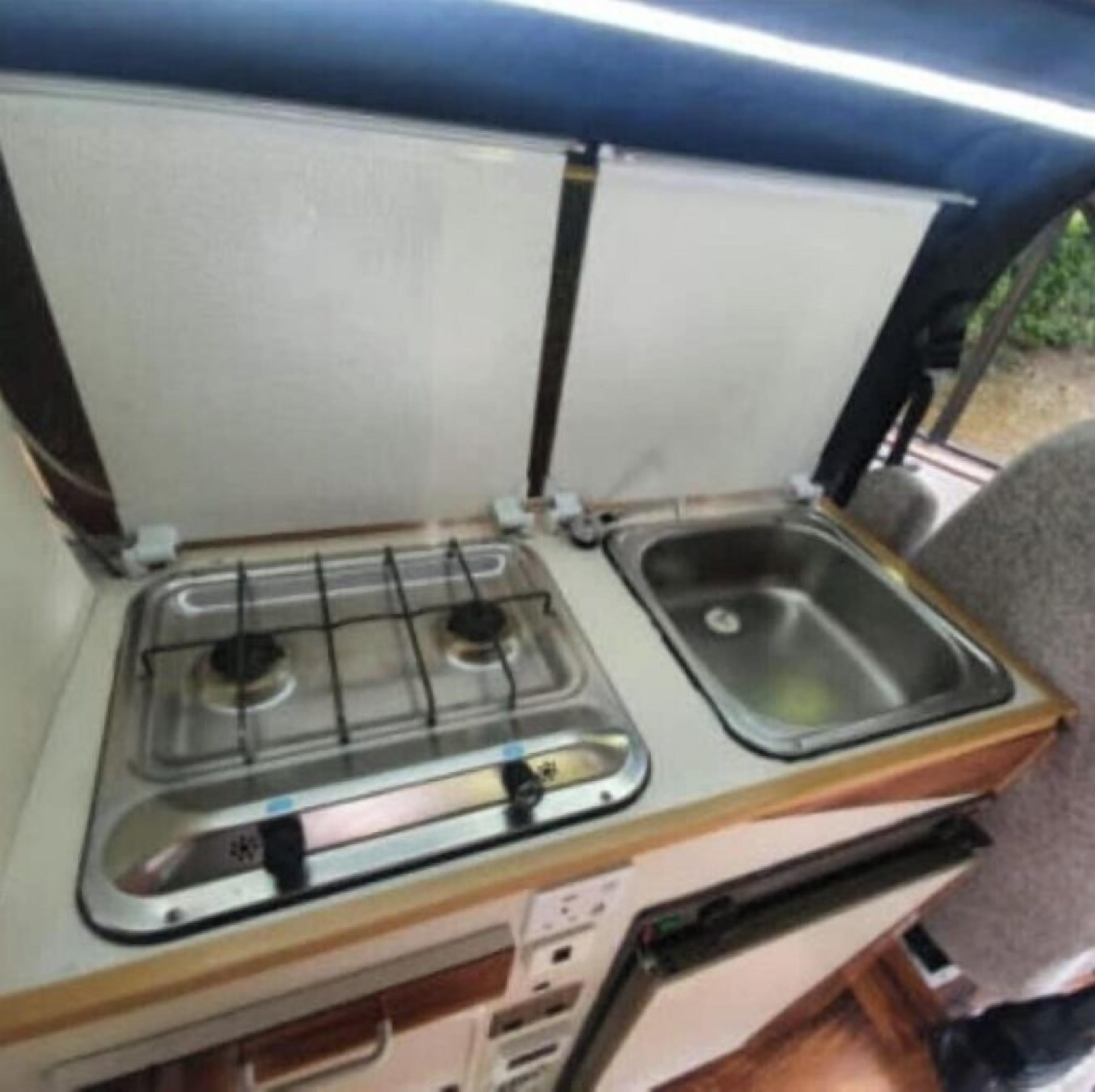 A compact kitchenette with a gas stove and a sink.