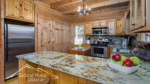 A kitchen with wooden cabinets, stainless steel appliances, and a marble countertop. - Trout Haven | No Pet Fees | Sleeps 6 | Creekfront | Outdoor pavillion w/ TV (Ellijay)