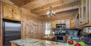 A kitchen with wooden cabinets, stainless steel appliances, and a marble countertop. - Trout Haven | No Pet Fees | Sleeps 6 | Creekfront | Outdoor pavillion w/ TV (Ellijay)