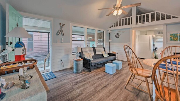A spacious living area with a high ceiling fan, a sofa, wooden flooring, and a dining table with chairs. - Everglades City Cabin: Dock & Heated Pool! (Everglades City)