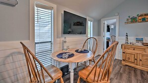 A dining area with a round wooden table, four wooden chairs, and a television mounted above the table. - Everglades City Cabin: Dock & Heated Pool! (Everglades City)
