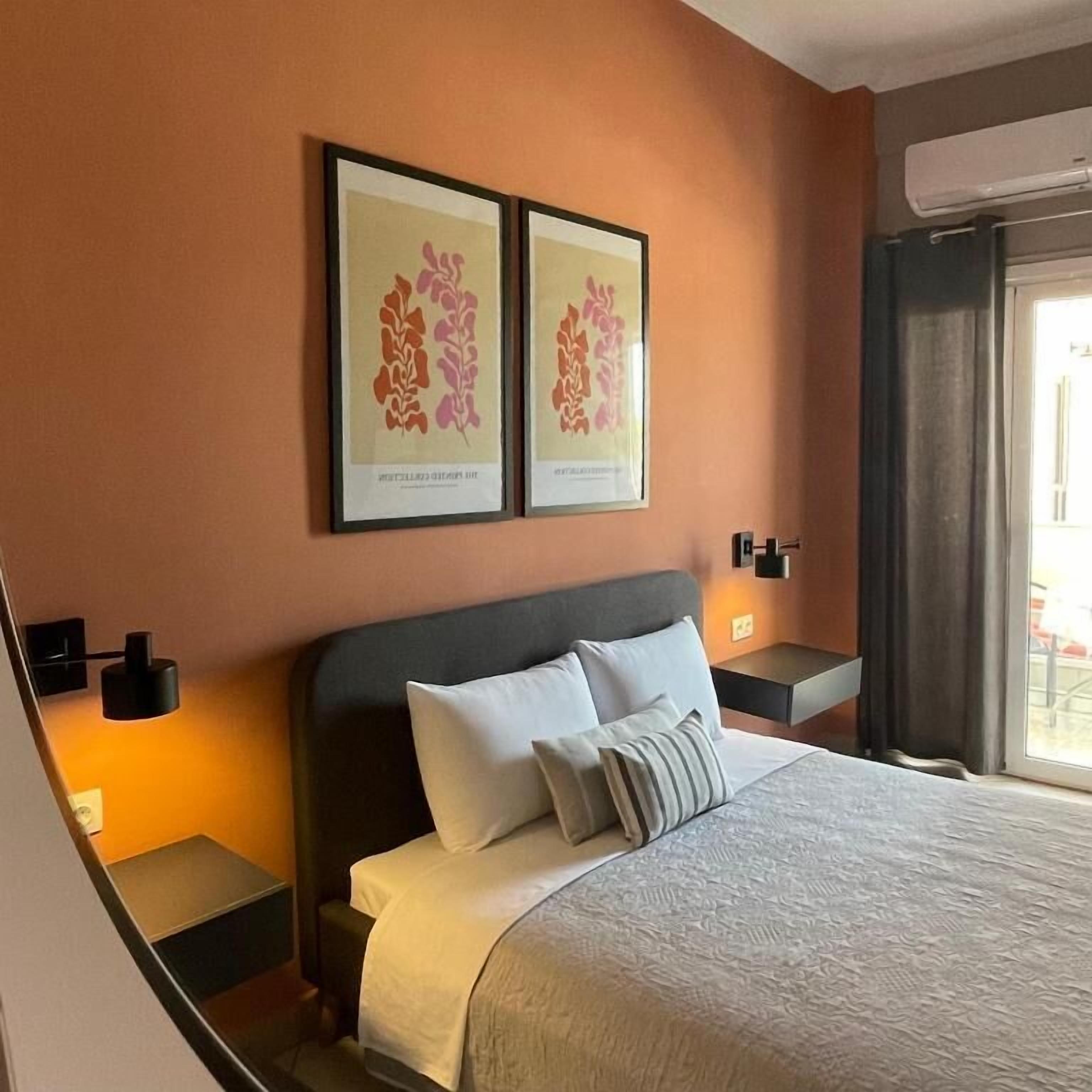Une chambre d’hôtel avec un grand lit, deux œuvres d’art encadrées au mur et une fenêtre avec des rideaux.
