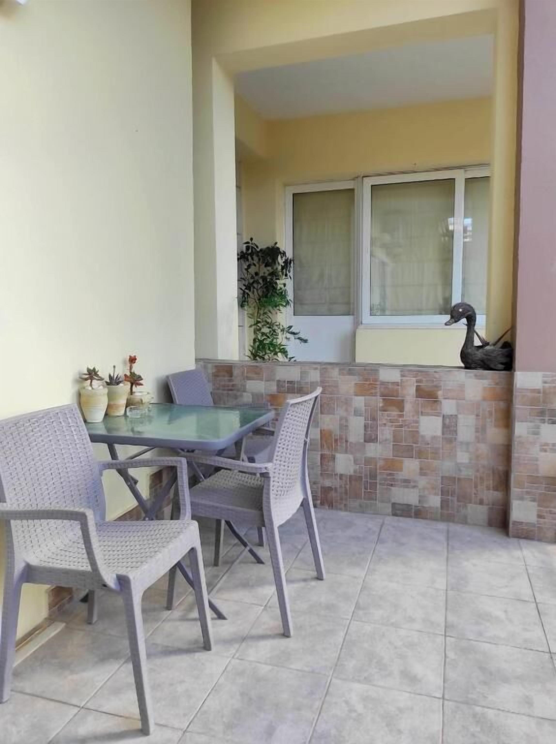 A patio with a glass table and four chairs, a potted plant, and a decorative duck.