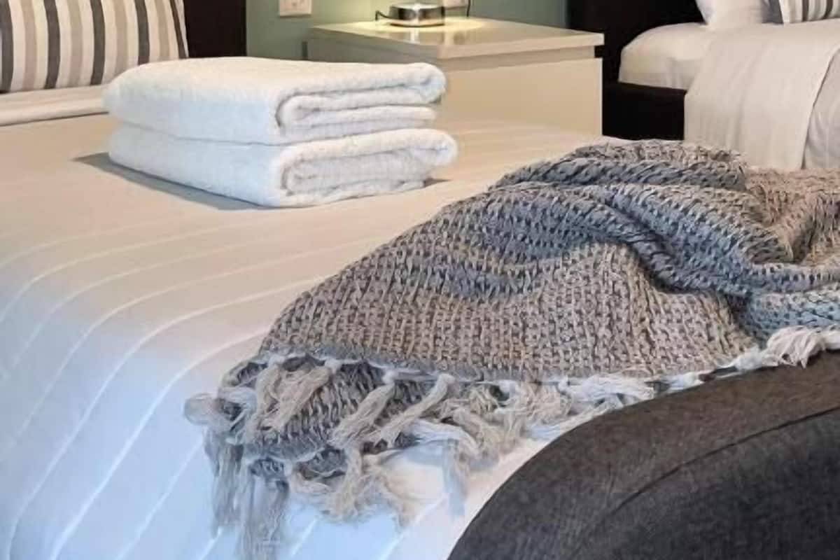 Ein Hotelzimmer mit zwei Betten, einem Nachttisch mit Lampe und Bildern an den Wänden.