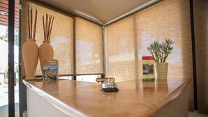 Un espace d’accueil avec un comptoir en bois, deux vases, un livre, une plante en pot et une cloche.
