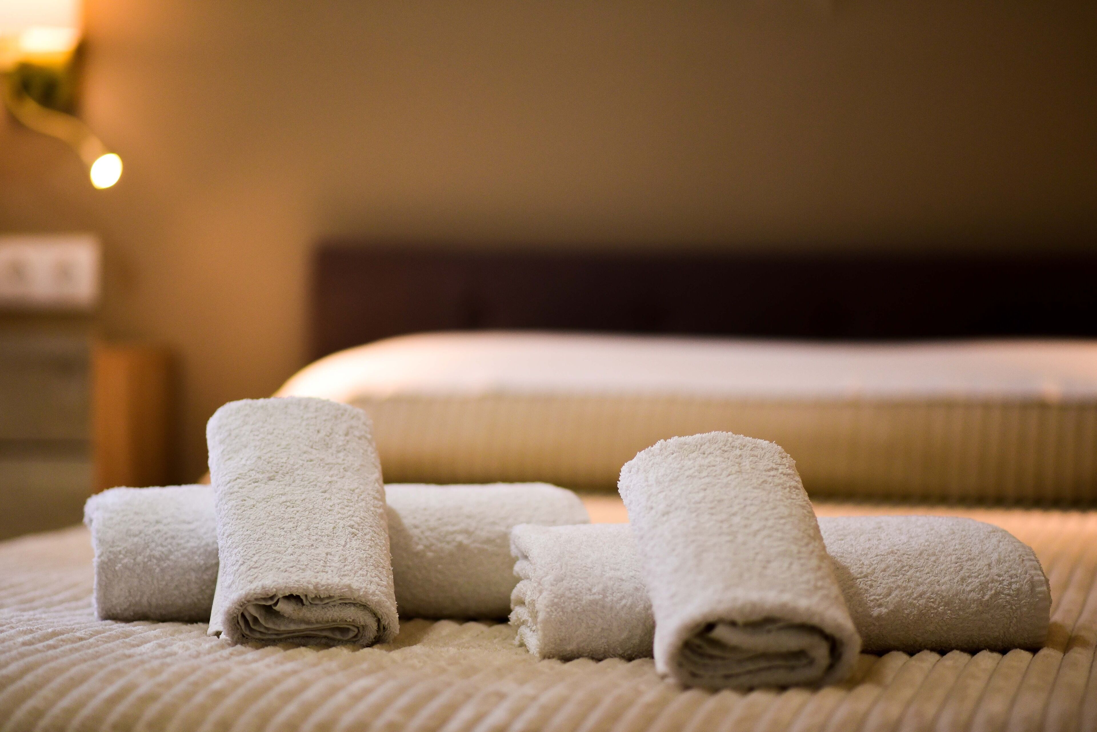 Un ensemble de serviettes blanches, soigneusement disposées, sur un couvre-lit texturé dans une chambre d’hôtel.