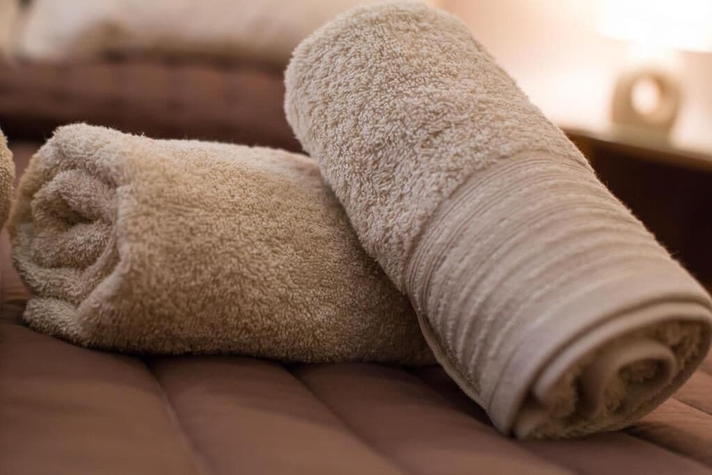 A neatly folded beige towel on a brown sofa.
