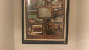 Een lijst met een poster waarop diverse historische en culturele taferelen te zien zijn, zoals een kasteel, een zeilschip en een kustlandschap.