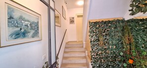 Een trap met een wandplantenwand en ingelijste kunstwerken.
