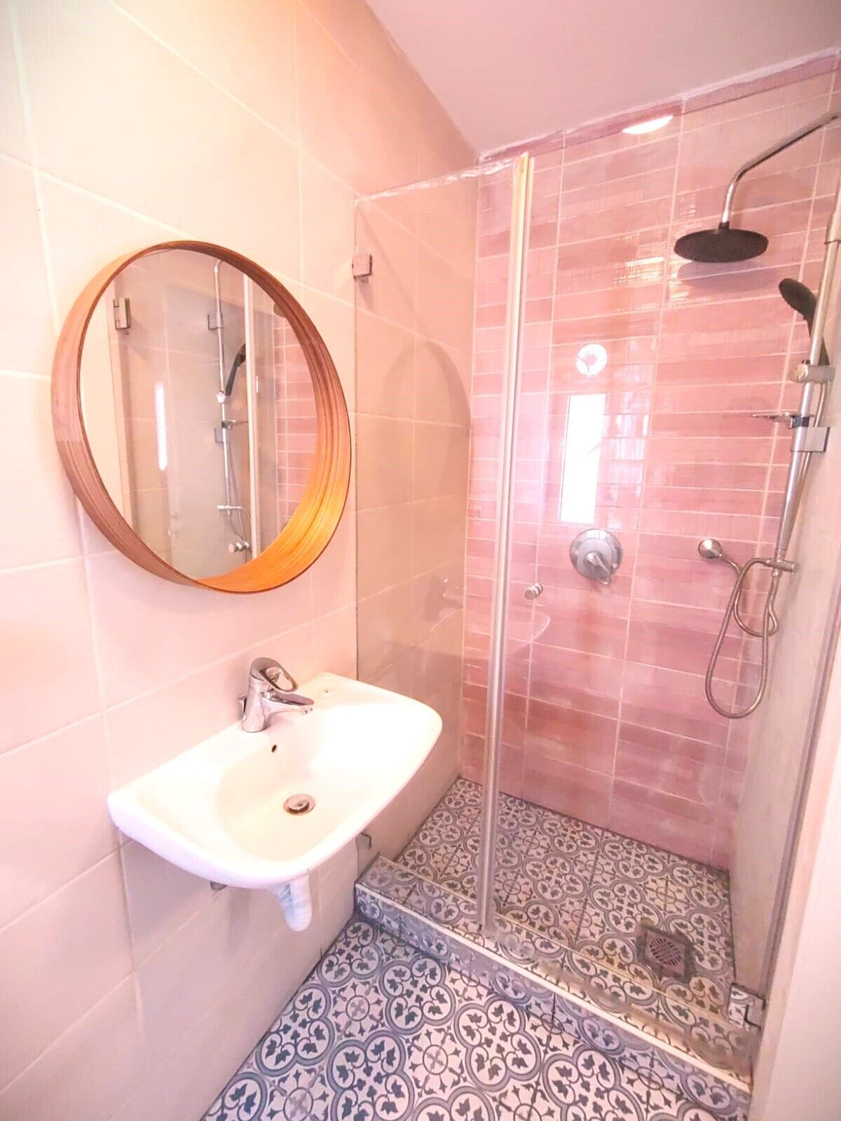 A bathroom with a sink, mirror, and shower.