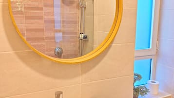 Un baño con un espejo redondo, un lavamanos y un inodoro.